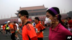 参加北京国际马拉松长跑的人在雾霾中跑过天安门，有些人带着口罩（2014年10月19日）