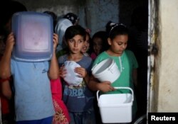 Children wait for meals provided through the initiative, Family Kitchen, which packages excess foods from five-star hotels to underprivileged families during the holy month of Ramadan, in Al-Baqaa Palestinian refugee camp, near Amman, Jordan, June 10, 2018.