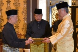 Perdana Menteri Malaysia Muhyiddin Yassin (kiri) menerima dokumen dari Raja Sultan Abdullah Sultan Ahmad Shah (kanan). (Foto: AFP)