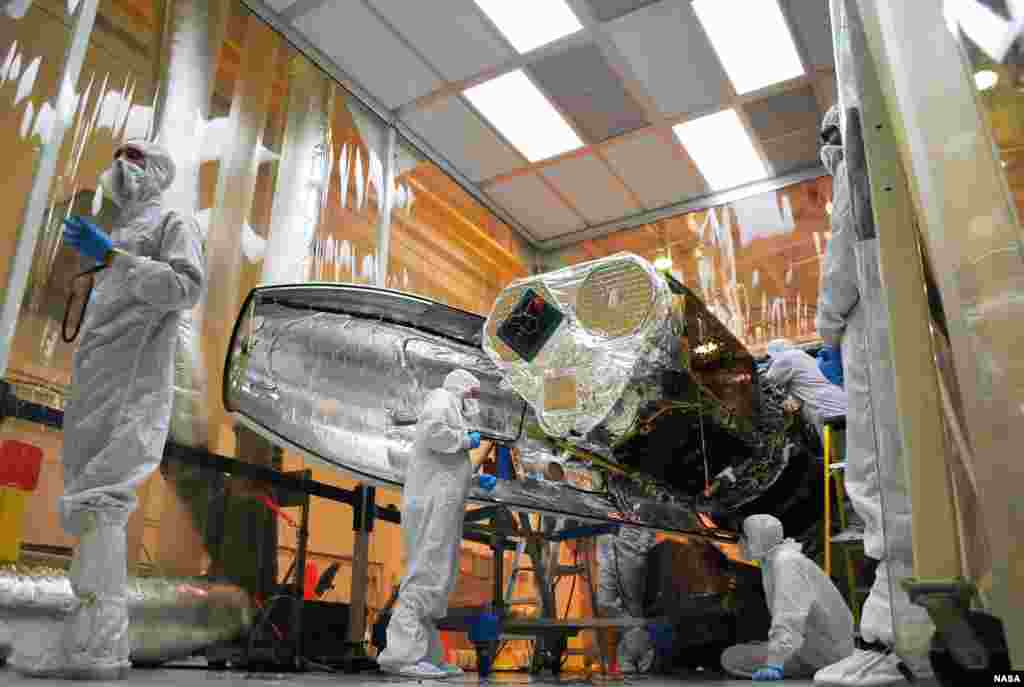 Technicians install one half of the payload fairing over the NuSTAR spacecraft as they continue to process the spacecraft and its Pegasus rocket for launch, May 22, 2012. (NASA)