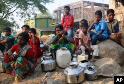 FILE - People wait to fill their vessels with water at a communal tap in Kukse Borivali, 85 kilometers (53 miles) northeast of Mumbai, India, April 12, 2016. Decades of groundwater abuse, populist water policies and poor monsoons have turned vast swaths of central and western India into a dust bowl.