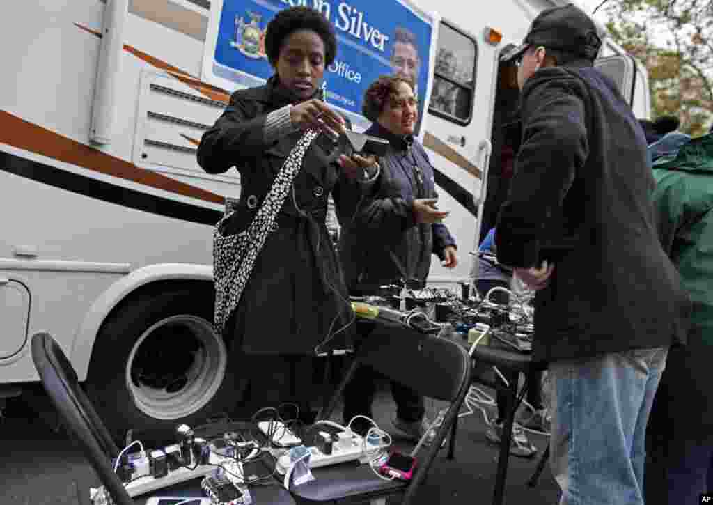 Tunisia Wragg, left, a staff member with New York Assemblyman Sheldon Silver, checks a cell phone at a charging station in Chinatown, NY, Nov 1, 2012.