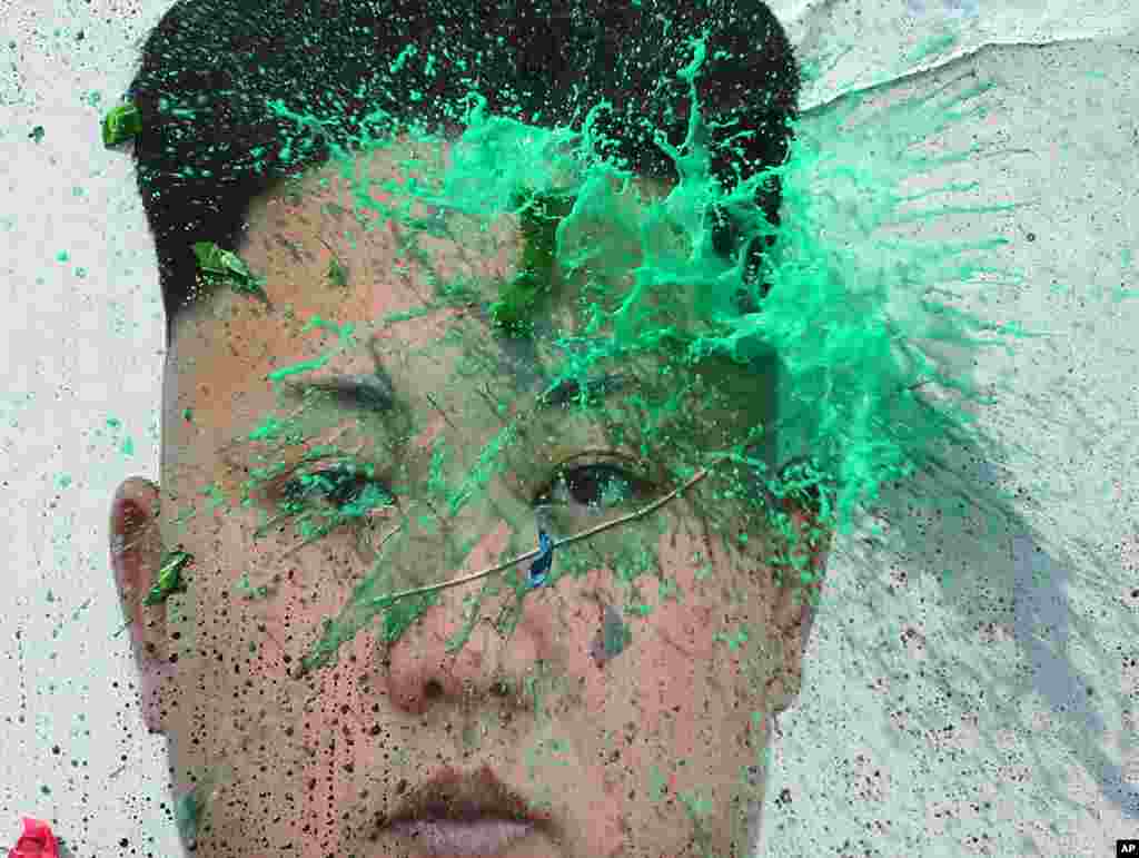 A balloon with a colored liquid, thrown by a North Korean defector bursts on a portrait of North Korean leader Kim Jong Un during a rally protesting North Korea, in Seoul, South Korea. 