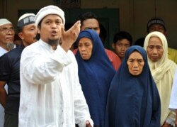 Ulama Dzulkarnain (kiri) meneriakkan slogan-slogan di samping Tariyem (kedua dari kanan) ibu dari terpidana pelaku bom Bali 2002 Amrozi dan Mukhlas, dan dua saudara perempuan (belakang) dalam kunjungan mendukung tiga pelaku bom Bali di Tenggulun pada 6 No