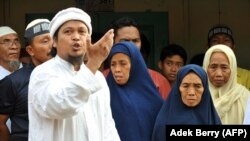 Ulama Dzulkarnain (kiri) meneriakkan slogan-slogan di samping Tariyem (kedua dari kanan) ibu dari terpidana pelaku bom Bali 2002 Amrozi dan Mukhlas sebagai ilustrasi. (Foto: AFP)