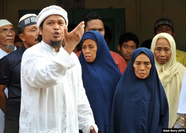 Ulama Dzulkarnain (kiri) meneriakkan slogan-slogan di samping Tariyem (kedua dari kanan) ibu dari terpidana pelaku bom Bali 2002 Amrozi dan Mukhlas, dan dua saudara perempuan (belakang) dalam kunjungan mendukung tiga pelaku bom Bali. (Foto: AFP)