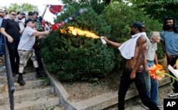 A counterprotester uses a lighted spray can against a white nationalist demonstrator at the entrance to Lee Park in Charlottesville, Virginia, Aug. 12, 2017. While President Donald Trump has said there were "some very bad people" on both sides, Charlottesville Mayor Mike Signer says he lays the blame for last weekend's event squarely on "Nazis and KKK members.