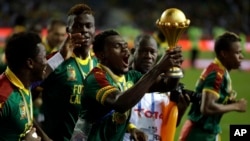 Cameroon players run celebrating with the trophy after winning the African Cup of Nations final soccer match between Egypt and Cameroon at the Stade de l'Amitie, in Libreville, Gabon, Sunday, Feb. 5, 2017. 