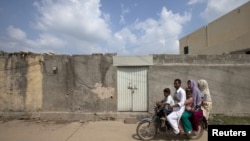 A family rides past the locked house of Rimsha Masih, a Pakistani Christian girl accused of blasphemy, on the outskirts of Islamabad, August 23, 2012.