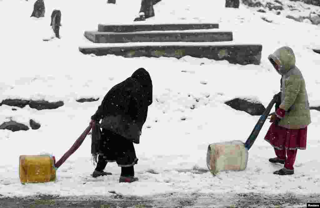 Children drag water containers as it snows in Kabul, Afghanistan.