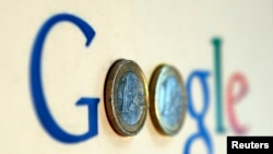 FILE - An illustration picture shows a Google logo with two one Euro coins, taken in Munich, Jan. 15, 2013. 