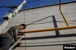 A worker installs gas pipes along the walls of residential houses in the village of Heqiaoxiang outside of Baoding, Hebei province, China, Dec. 5, 2017.