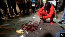 A man squats near a pool of blood where a man was injured Wednesday during protests in Charlotte, N.C.