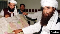 FILE - Jalaluddin Haqqani, right, the Taliban's Minister for Tribal Affairs, points to a map of Afghanistan during a visit to Islamabad, Pakistan, Oct. 19, 2001, as his son Naziruddin, left, looks on.