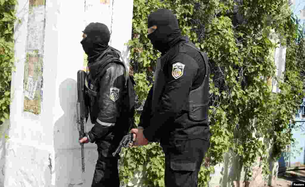 Police officers stand ready with guns drawn outside parliament in Tunis, March 18, 2015.