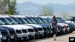 FILE - A lot technician passes by a long line of unsold 2018 and 2019 Countryman models at a Mini dealership in Highlands Ranch, Colorado, Aug. 30, 2018.