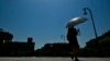 Seorang perempuan menggunakan payung untuk melindungi dari panas musim panas di Pamplona, utara Spanyol, Jumat, 28 Juni 2019. (Foto: AP)