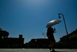 Seorang perempuan menggunakan payung untuk melindungi dari panas musim panas di Pamplona, utara Spanyol, Jumat, 28 Juni 2019. (Foto: AP)