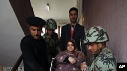 A woman on a wheelchair is helped down the stairs by army soldiers and policemen after casting her vote on the second day of parliamentary elections in Cairo November 29, 2011