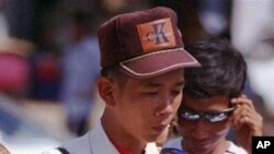 A Cambodian vendor wearing many kinds of glasses on his front shirt, cleans a sun glasses to sell in the Olympic stadium.