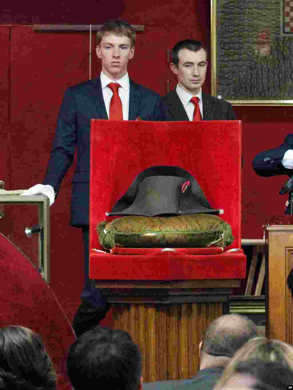 Employees stand behind one of Napoleon&#39;s hat at its auction in Fontainebleau, South of Paris. Napoleon Bonaparte&#39;s famous bicorn hat was sold 1.5 million euros, $1,930,000.