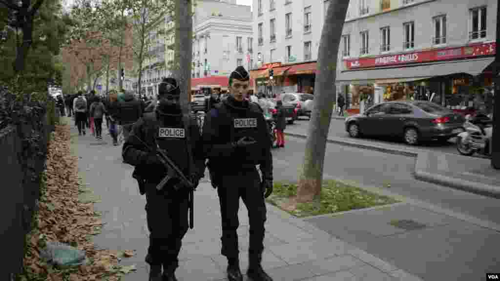 Polisi berpatroli dekat sebuah memorial di luar gedung konser Bataclan sehari setelah serangan teror di Paris (14/11).
