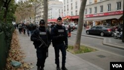 Policías patrullan cerca de un tributo levantado afuera de la sala de conciertos Bataclan en París un día después de que más de 120 personas fueran masacradas en una serie de ataques coordinados. Nov. 14 de 2015.