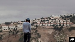FILE - A Jewish settler looks at the West bank settlement of Maaleh Adumim, from the E-1 area on the eastern outskirts of Jerusalem. West Bank settlement construction surged during the first year of the Trump presidency, an Israeli monitoring group said Sunday, releasing data that added to Palestinian mistrust of the American administration. Peace Now said that Israel began construction of 2,783 settlement homes in 2017. 