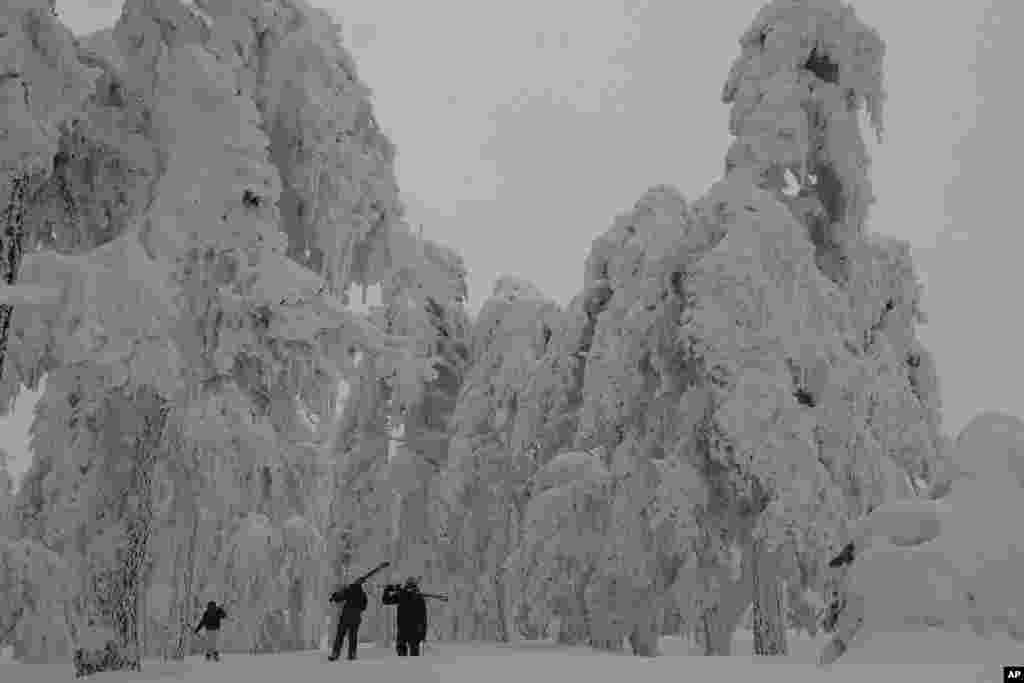 Men with their skis walk during a heavy snowfall on the Troodos mountains in Cyprus.