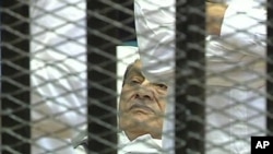 This video image taken from Egyptian State Television showing former Egyptian president Hosni Mubarak laying on a hospital bed flanked by his two sons Gamal and Alaa, inside a cage of mesh and iron bars in a Cairo courtroom, Wednesday Aug. 3, 2011, as hi