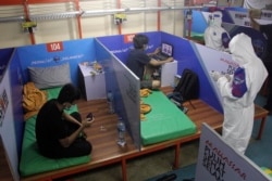 Petugas kesehatan mengenakan APD memeriksa pasien COVID-19 di bilik mereka di atas KM Umsini, kapal penumpang yang dijadikan pusat isolasi bagi mereka yang memiliki gejala ringan, di Pelabuhan Soekarno-Hatta, Makassar, Sulawesi Selatan, Minggu, 8 Agustus 2021. (AFP)