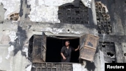 Un trabajador mira a través de la ventana de una fábrica severamente dañada en Deirl al-Balah, en la Franja de Gaza.
