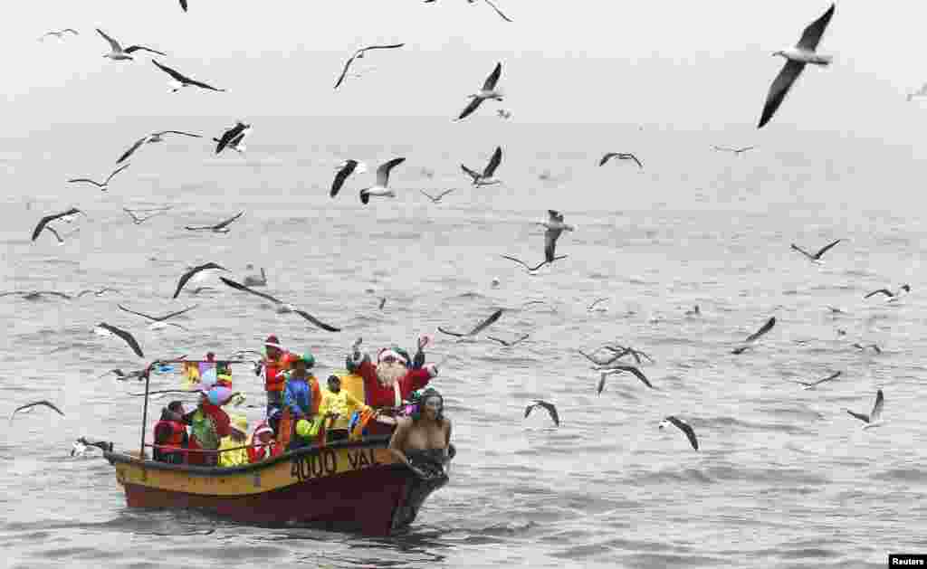 Ruben Torres, dressed in a Santa Claus outfit, waves to people from a boat with fishermen on Christmas Eve, along the coast of Valparaiso city, about 121 km (75 miles) northwest of Santiago, Chile.