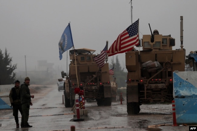 FILE - A line of U.S. military vehicles drive through a checkpoint of the Internal Security Forces in Manbij as they head to their base on the outskirts of the northern Syrian city, Dec. 30, 2018.