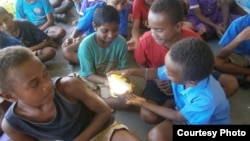 In a remote village in Fiji, children get a chance to learn about renewable energy as part of their curriculum and try out a new solar powered lamp donated to the school. (Energy for All)