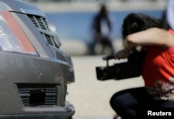 FILE - A member of the media photographs the front-end sensors of a 2011 Cadillac SRX autonomous car created by students and staff of Carnegie Mellon University, June 24, 2014, in Washington.