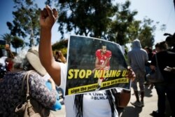 Seorang pengunjuk rasa memegang foto Colin Kaepernick untuk mendukung pemain NFL yang "berlutut" sebelum kickoff dan selama Lagu Kebangsaan memprotes kekerasan polisi, California, AS, 1 Oktober, 2017. (Foto: REUTERS/Danny Moloshok)