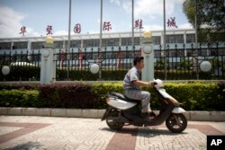 A man rides a motorbike outside of a Huajian Group shoe factory in Ganzhou in southeastern China's Jiangxi Province, June 6, 2017.