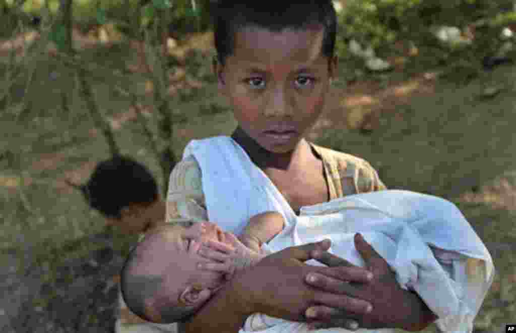In this photo taken on Nov. 8, 2012, a Rakhine boy carries a baby at a relief camp in Mrauk-U, Rakhine state, western Myanmar. Mrauk-U itself has been spared the bloodshed between the Buddhist Rakhine and the Muslim Rohingya that has scarred other parts o