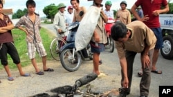 Cư dân vây quanh một chiếc xe máy bị cháy thành than trong tỉnh Nghệ An. Dân làng phẫn nộ vì bị trộm chó đã thu giữ xe máy của các tên trộm chó và nổi lửa đốt xe.