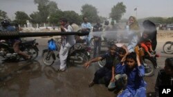 A Pakistani volunteer sprays water on people to keep them cool as temperatures reached 43 Celsius (109.4 Fahrenheit) in Karachi, Pakistan, May 21, 2018. 