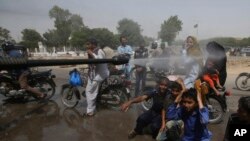 Un volontaire au Pakistan asperge d'eau sur les passants alors qu'il fait 43 degrés à Karachi, Pakistan, 21 mai 2018. 
