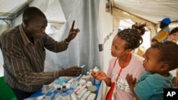 Yared, 2, is held by mother Madhn who fled from the town of Bor a few days ago, receive medicine for her child at a Medecins Sans Frontieres (MSF) medical tent, at a United Nations compound which has become home to thousands of displaced people.