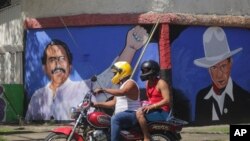 A motorcyclist rides past a mural of Nicaraguan President Daniel Ortega, left, and revolutionary hero Cesar Augusto Sandino during general elections in Managua, Nicaragua, Nov. 7, 2021.