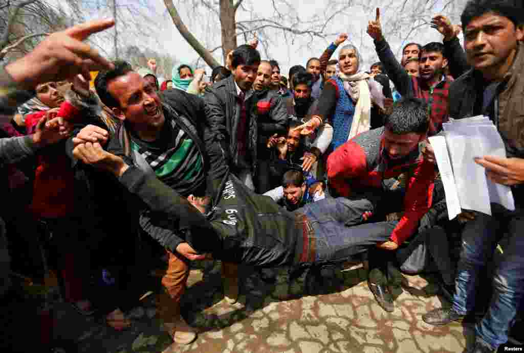 People carry an unconscious teacher after he was injured in clashes with the Indian police during a protest by teachers demanding the regularization of their contractual jobs and hike in salaries, in Srinagar.