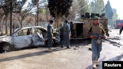 Афганские полицейские осматривают поврежденый армейский автомобиль после теракта в провинции Гильменд, Афганистан. 11 февраля 2017.
