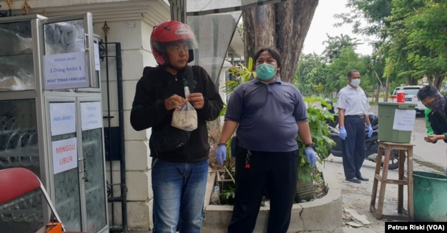 Para pengemudi ojek online mengambil nasi bungkus gratis untuk makan siang. (Foto: VOA/Petrus Riski)