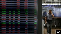 A man speaks his on his cellphone next to an index board at the reception hall of the Stock Exchange in Athens, July 25, 2017. Greece tapped international bond markets for the first time in three years on July 25, 2017. 