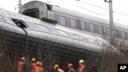 Workers inspect a damaged railway carriage not far from the village of Uglovka in Russia's Novgorod region on November 28, 2009, as it traveled between Moscow and Saint Petersburg