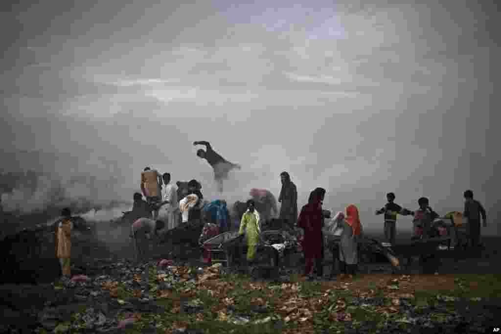 Pakistanis, survey woods from a burning field, which was used by fruit and vegetable sellers to store their wooden boxes, on the outskirts of Islamabad. 